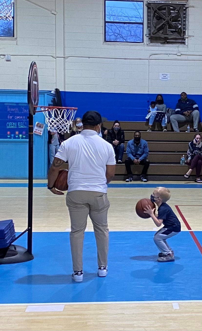 Kid wearing a blue shirt preparing to throw a basketball.